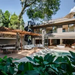 Fachada da Casa Ismael integrada ao jardim e ao deck de madeira