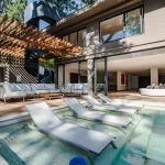 Piscina com espreguiçadeiras submersas diante da fachada